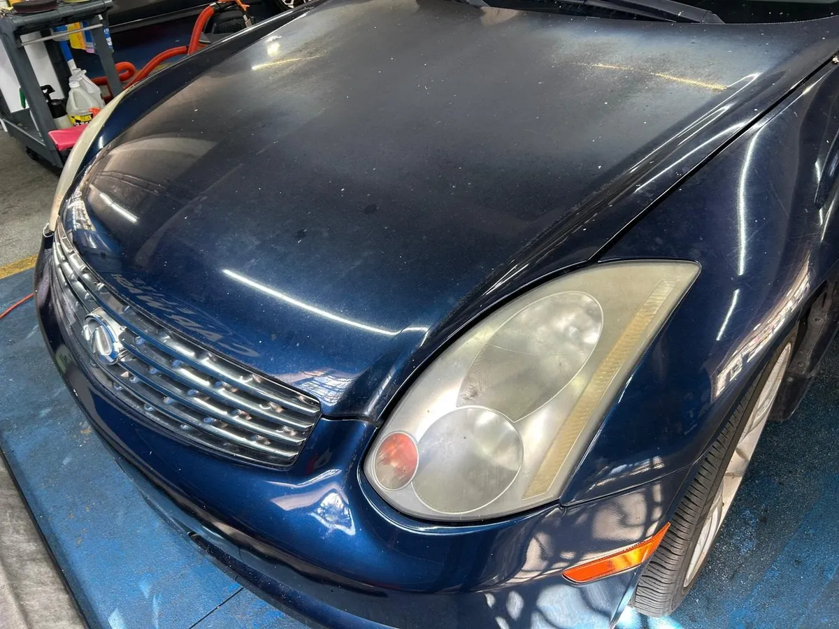 Blue Infiniti coupe before detailing, with cloudy yellowed headlights and dull paint