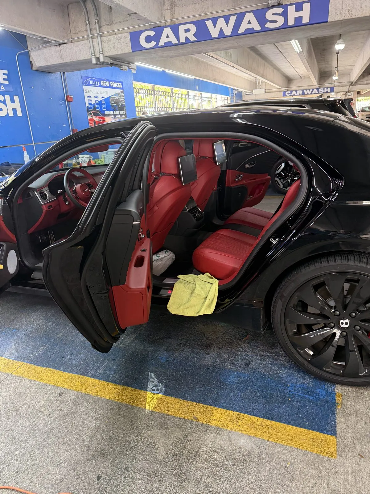 Black sedan with red leather interior, doors open for interior detailing