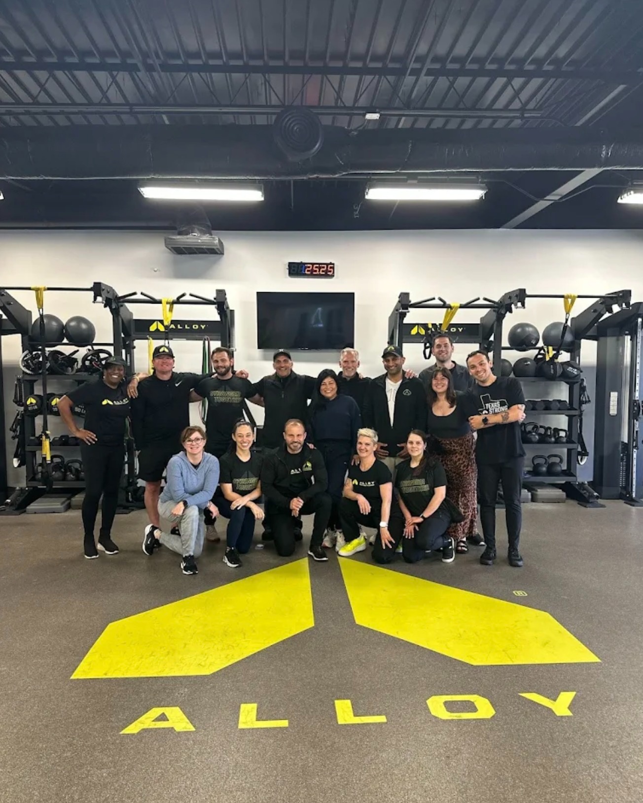 Group of certified personal trainers and members inside Alloy Personal Training South Tampa studio during small group fitness training focused on strength training, functional fitness, and personalized coaching for adults over 40.