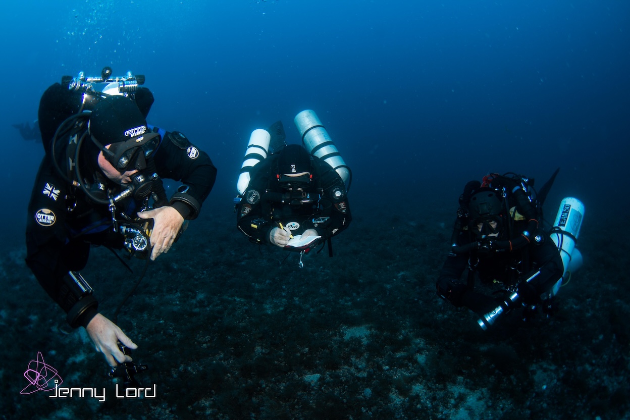 Speaker on a low-light stage presenting to divers