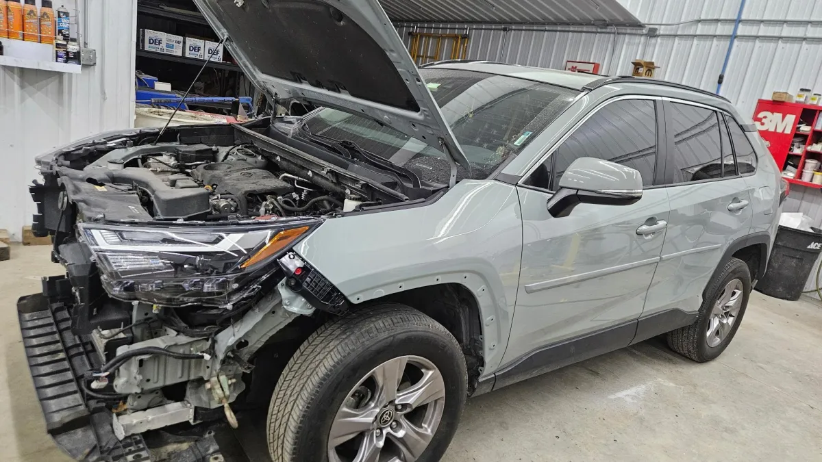 Silver SUV with front-end collision damage at Legacy Automotive collision repair shop in Hastings, MI