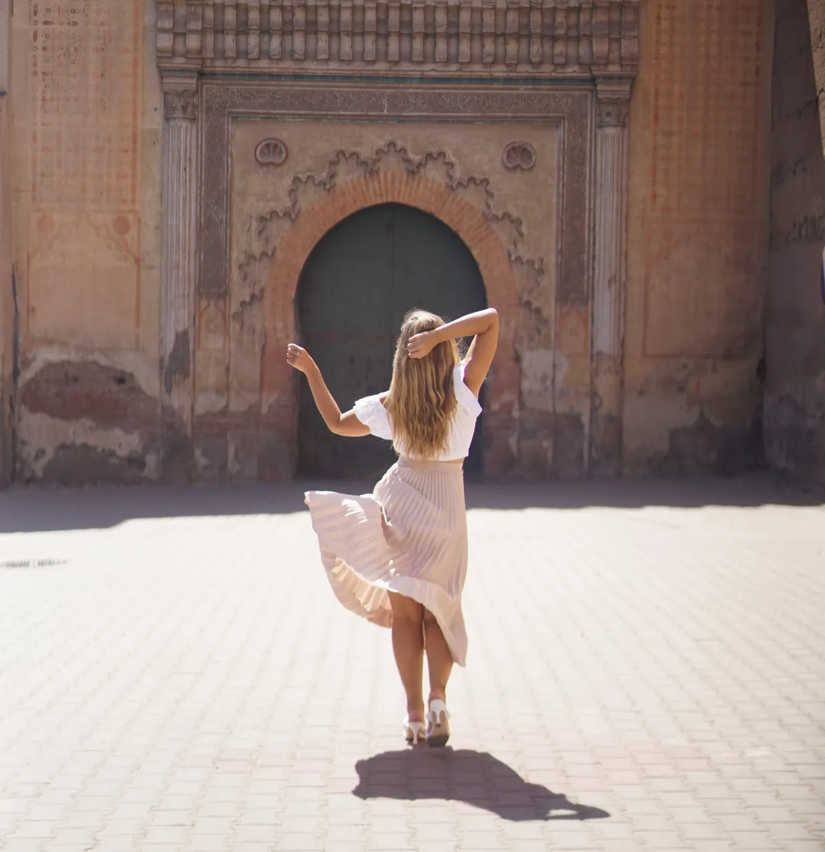 Woman walking toward an ornate archway in sunlight, symbolizing stepping away from misaligned business and starting a new chapter in business coaching for established consultants.