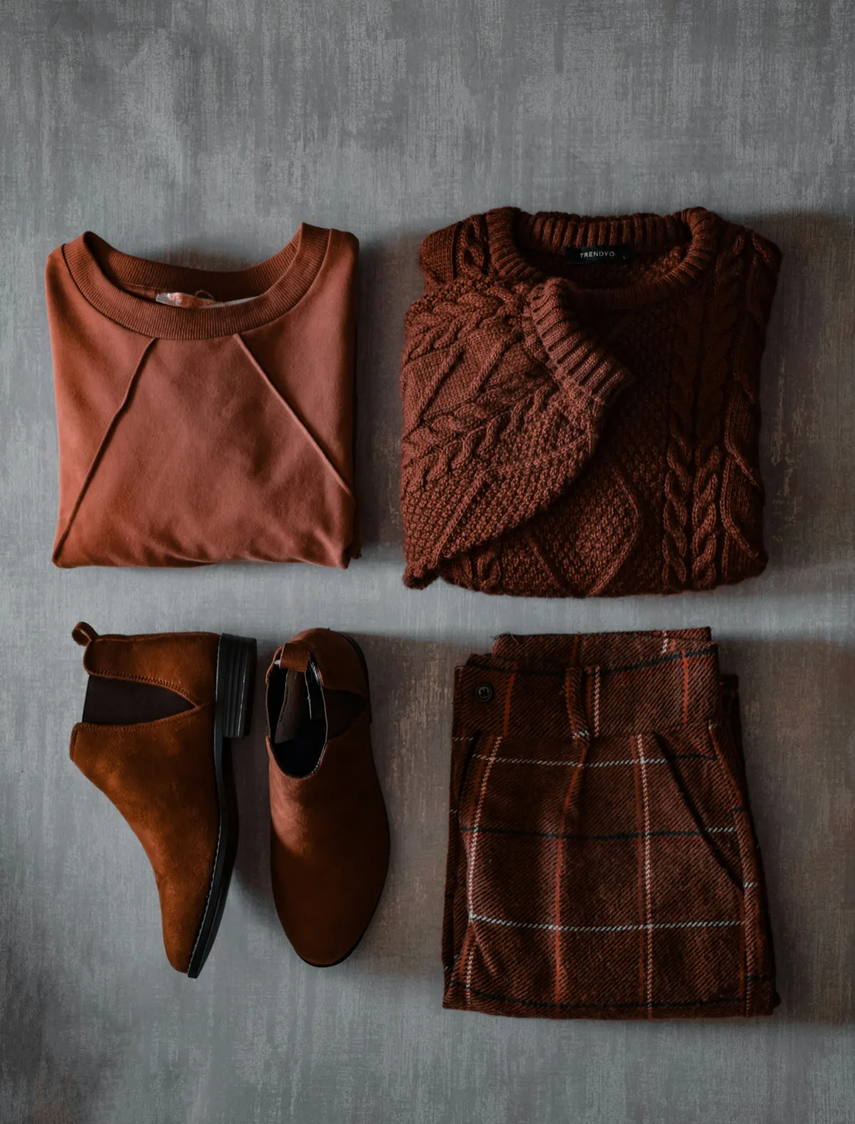 Flat lay of a complete outfit with sweater, skirt and boots