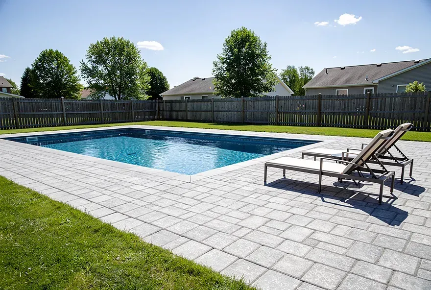 Newly installed light gray paver pool deck surrounding a backyard pool in Taylor, Michigan.