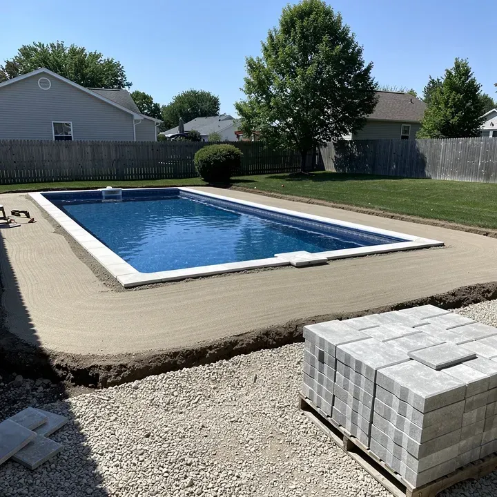 Paver pool deck installation in progress around a backyard pool in Rosemead, California