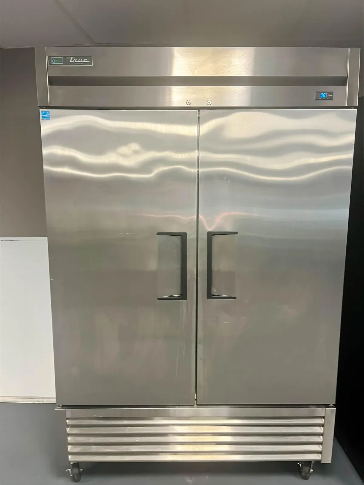 Man holding red peppers in a kitchen.