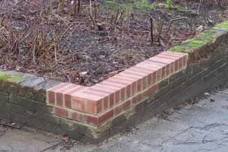 Brick masonry repair on landscape retaining wall 