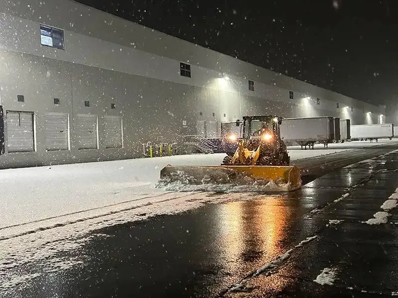 Commercial skid steer and salting fleet clearing open parking acreage of large medical complex and regional shopping center