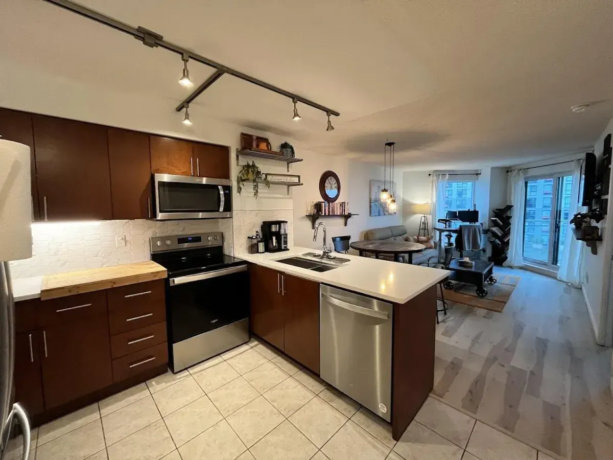 Modern kitchen at 410 Queens Quay W #812 featuring custom maple cabinetry, stainless steel appliances, and a functional pantry.