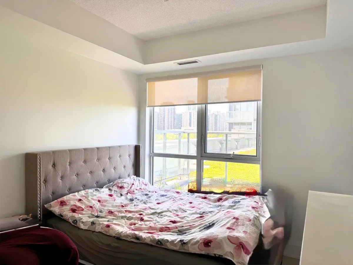Spacious bedroom in suite 901 with large windows, neutral tones, and a view of the green roof terrace.
