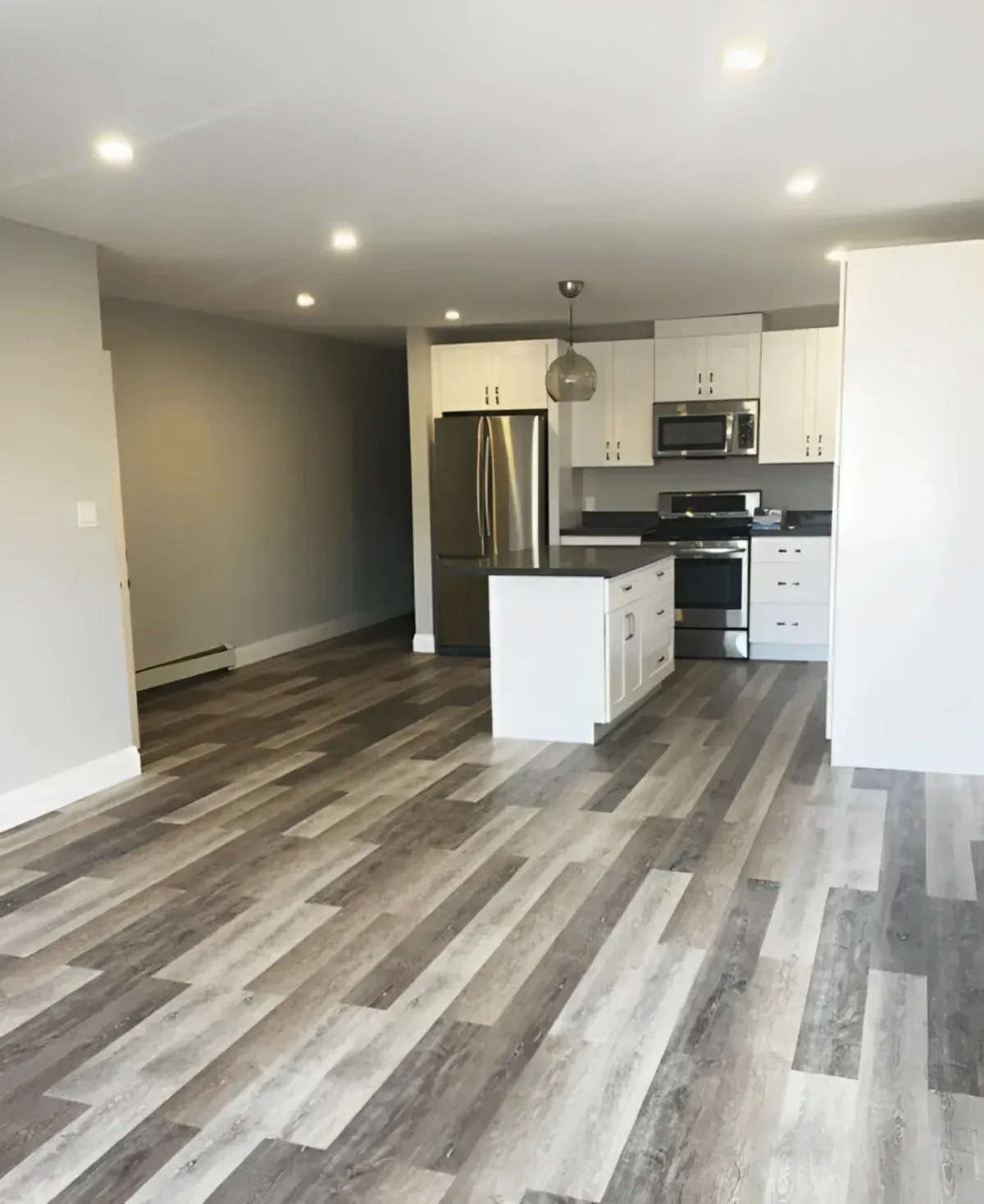 Modern kitchen at 36 Branstone Rd #1 featuring white cabinetry, quartz countertops, a central island, and stainless steel appliances.
