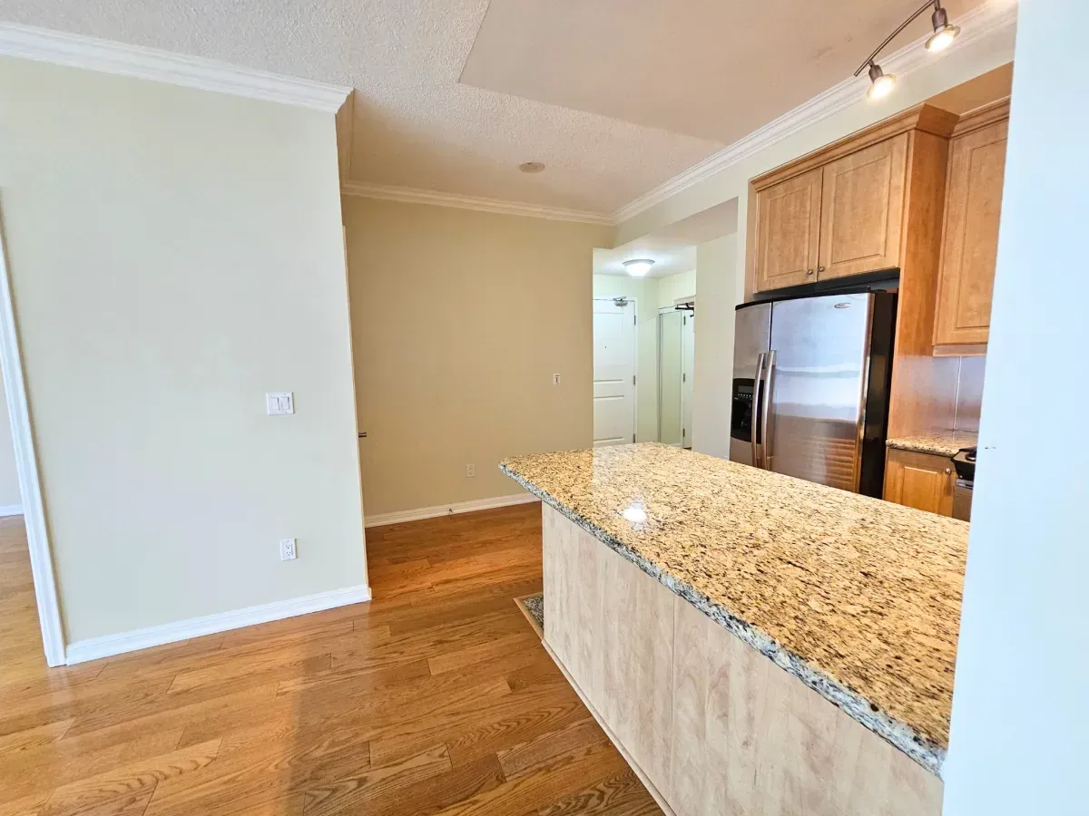 Open-concept kitchen with rich cabinetry and premium stone counters in a West Harbour City condo.