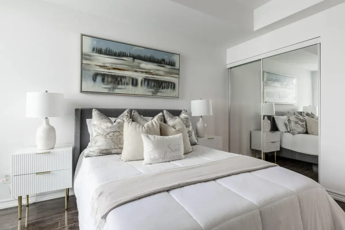 Spacious primary bedroom at 5 Marine Parade Dr #630, Etobicoke, featuring mirrored closets, hardwood floors, and balcony access.