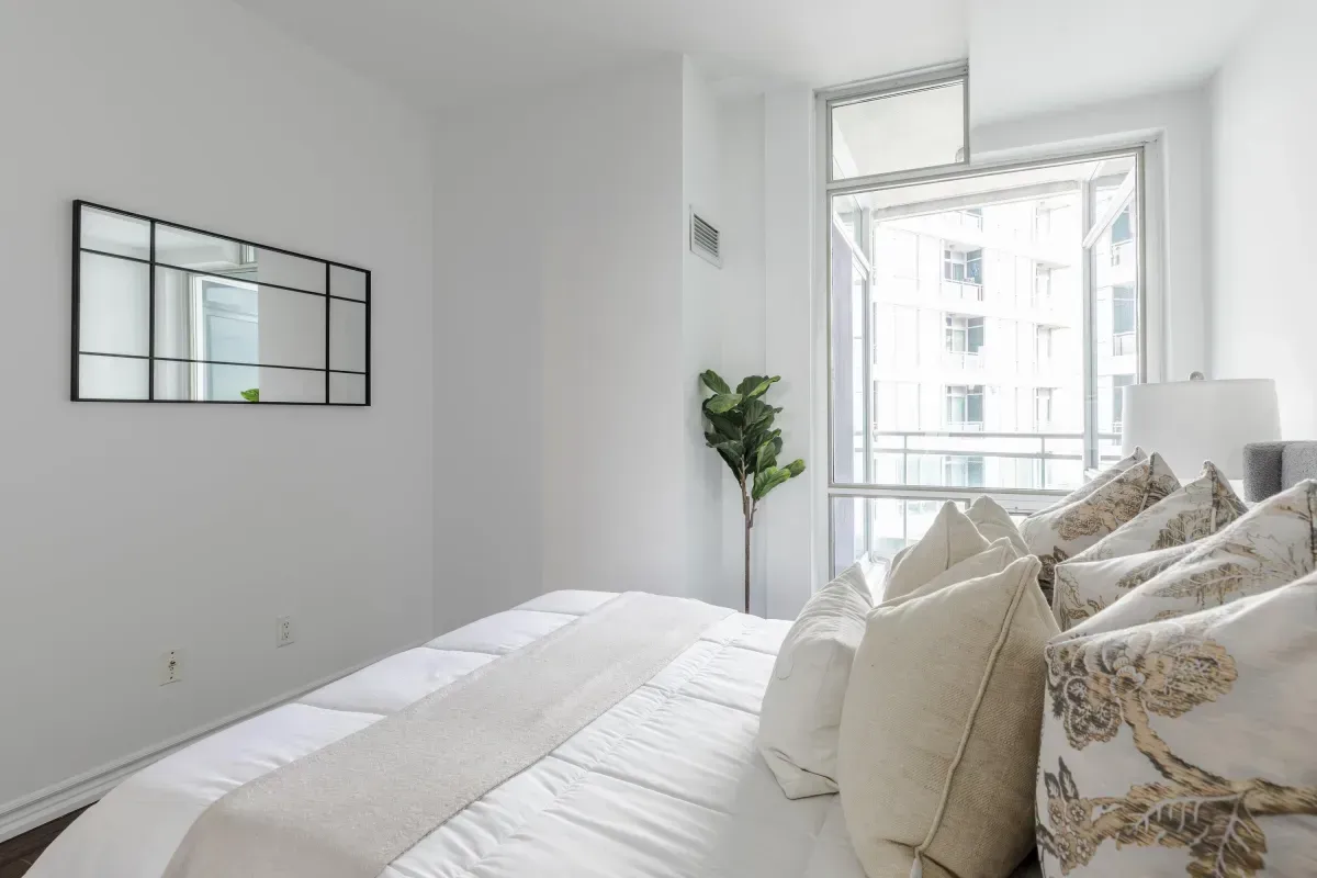 pacious primary bedroom at 5 Marine Parade Dr #630, Etobicoke, featuring mirrored closets, hardwood floors, and balcony access.
