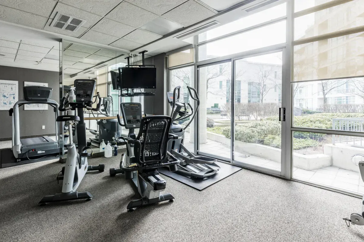 Bright, glass-walled gym at 5 Marine Parade Dr #630, Etobicoke, equipped with professional-grade cardio and strength training machines.
