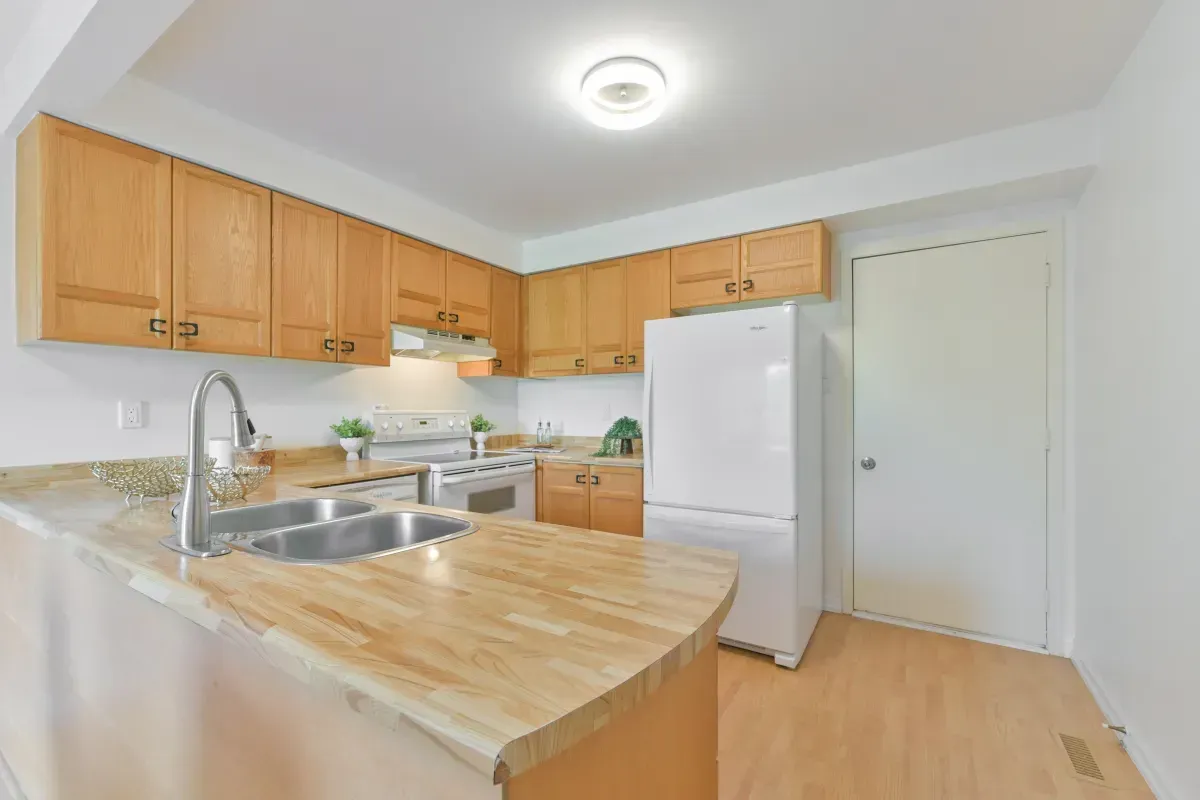 Functional kitchen with wood cabinetry, updated appliances, and a breakfast bar at 2286 Margot St, Oakville.