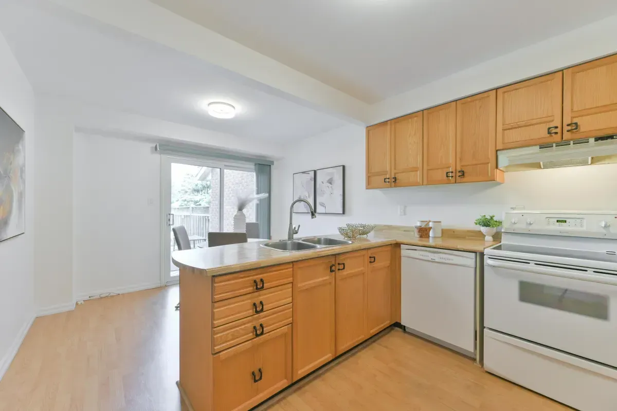 Functional kitchen with wood cabinetry, updated appliances, and a breakfast bar at 2286 Margot St, Oakville.