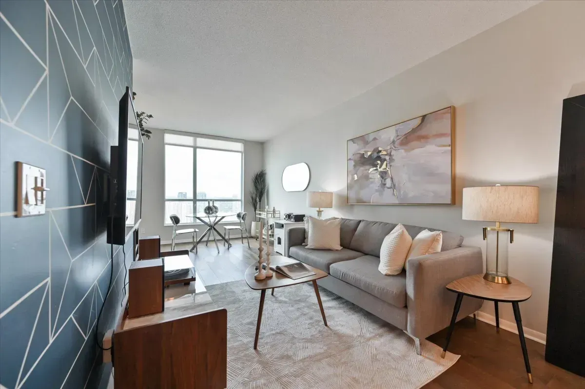 Open-concept living room at 219 Fort York Blvd featuring a blue accent wall and floor-to-ceiling windows.