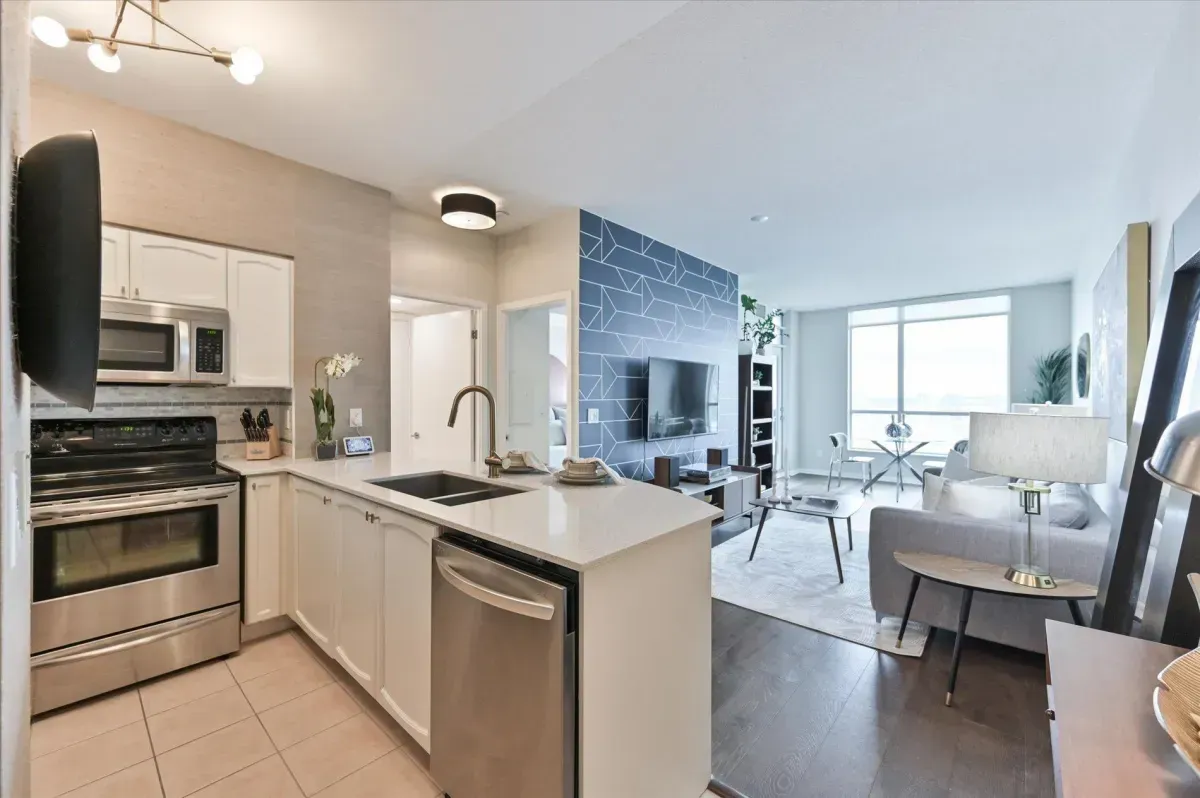 Renovated gourmet kitchen at 219 Fort York Blvd #3301 featuring white cabinetry, stone countertops, and stainless steel appliances.