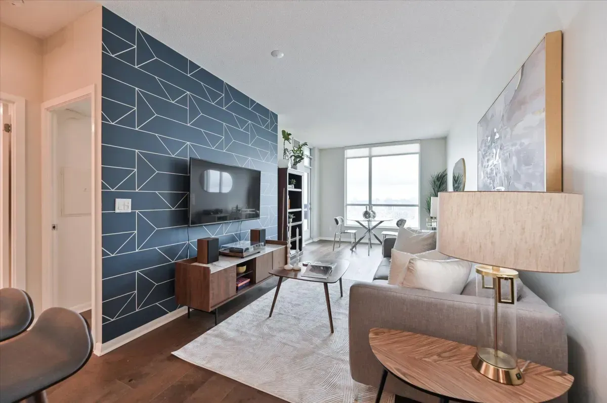 Open-concept living room at 219 Fort York Blvd featuring a blue accent wall and floor-to-ceiling windows.