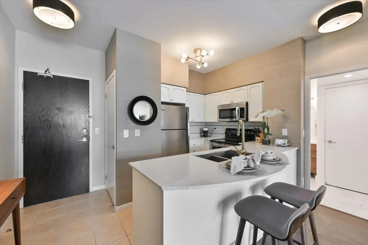 Renovated gourmet kitchen at 219 Fort York Blvd #3301 featuring white cabinetry, stone countertops, and stainless steel appliances.