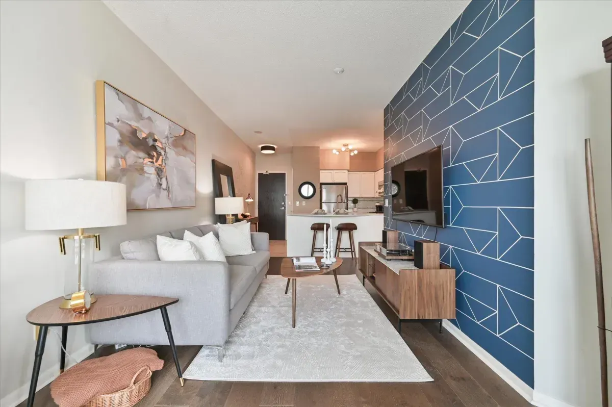 Open-concept living room at 219 Fort York Blvd featuring a blue accent wall and floor-to-ceiling windows.