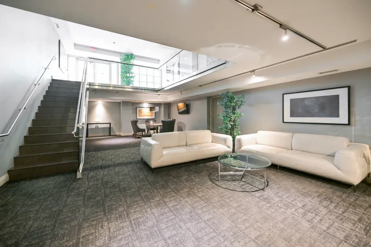 Two-story designer resident lounge with modern white sofas and grand staircase at King West Condominiums, 85 E Liberty St.