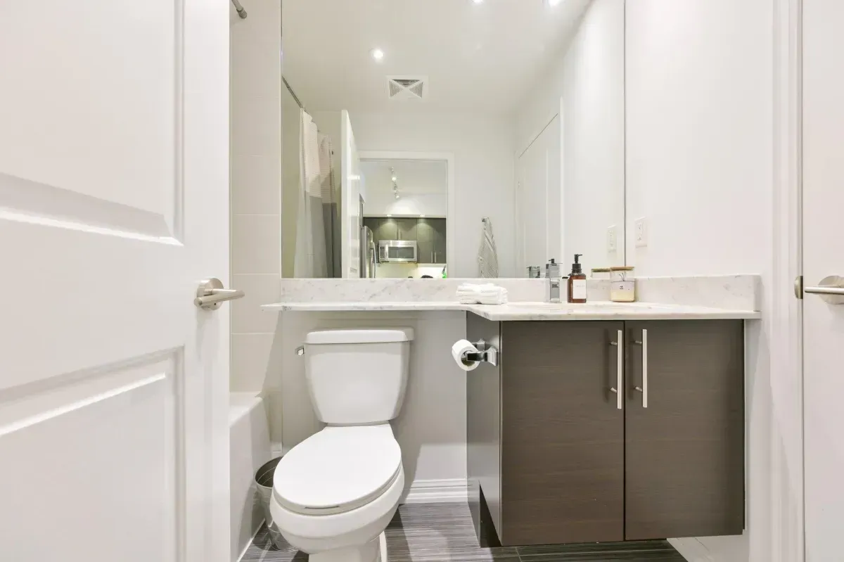 Clean, contemporary bathroom with dark wood vanity and integrated shower/tub at King West Condos.