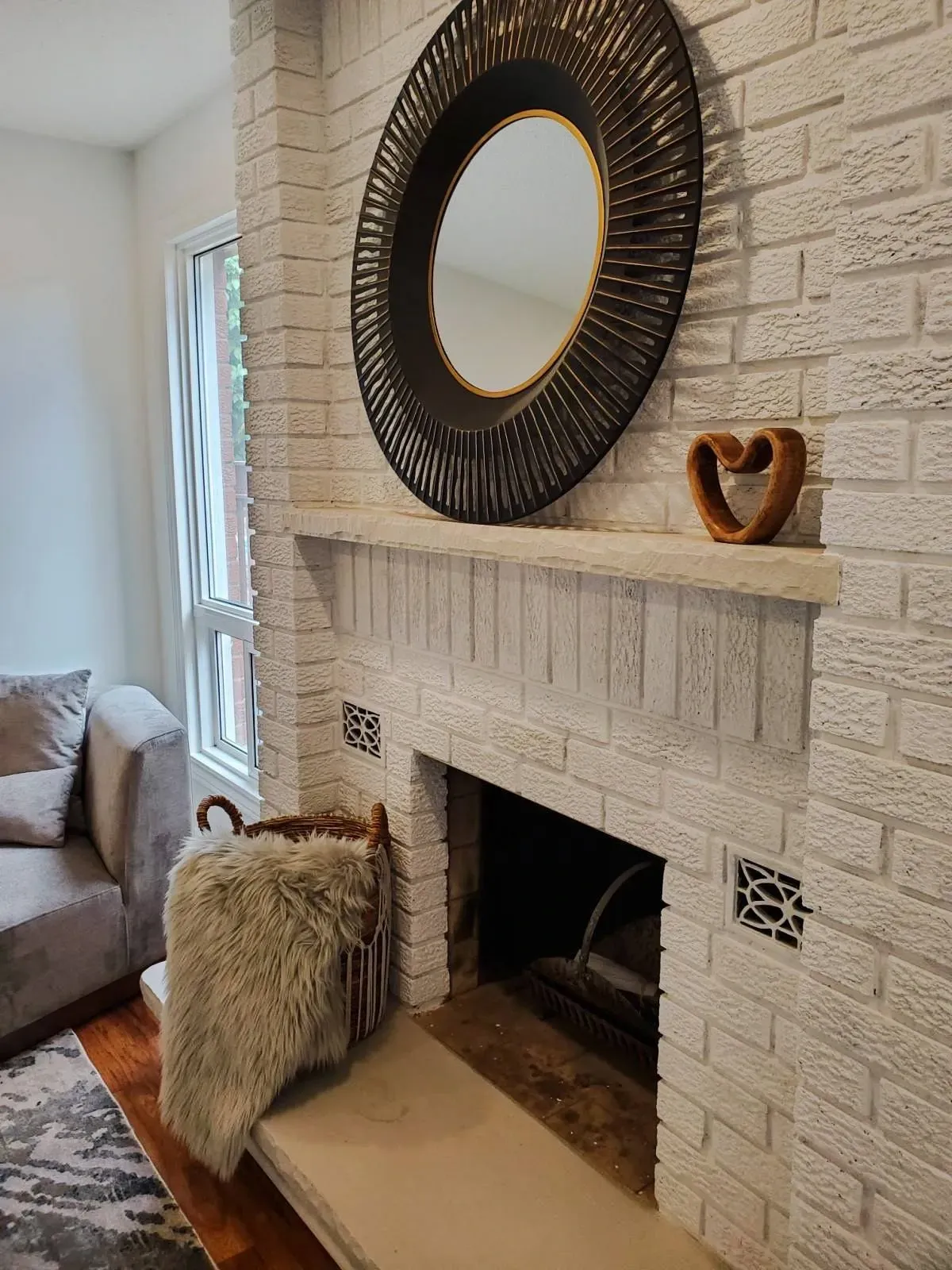 Close-up of the floor-to-ceiling white brick fireplace with rustic wood accents at 110 Holliday Dr.