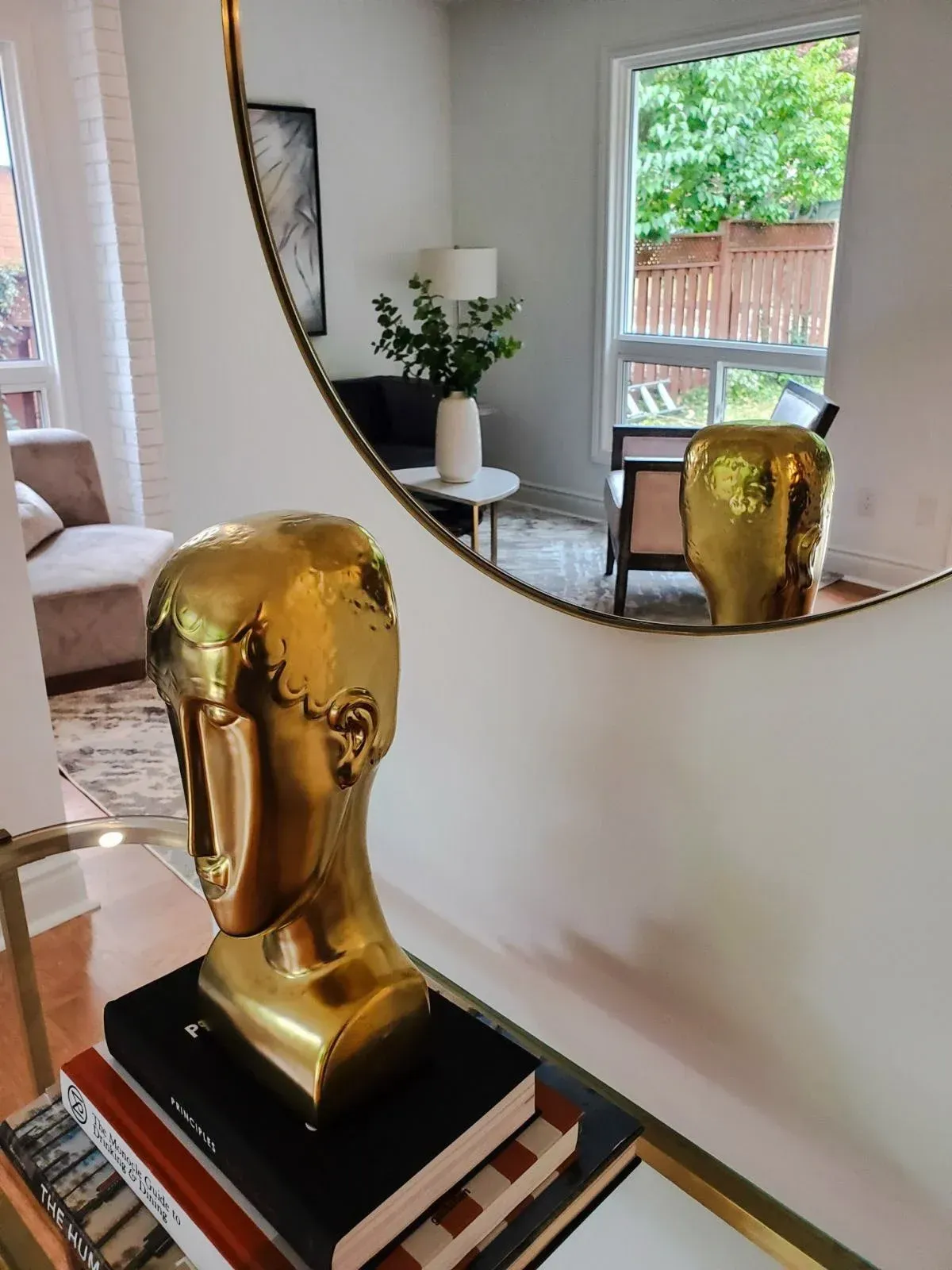 Detail of the modern foyer at 110 Holliday Dr with a gold sculpture and large circular mirror.