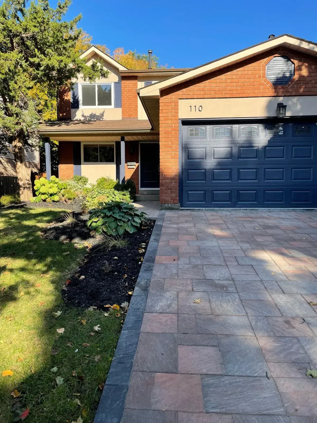 Street-side view of 110 Holliday Dr with a focus on the manicured front lawn and driveway.
