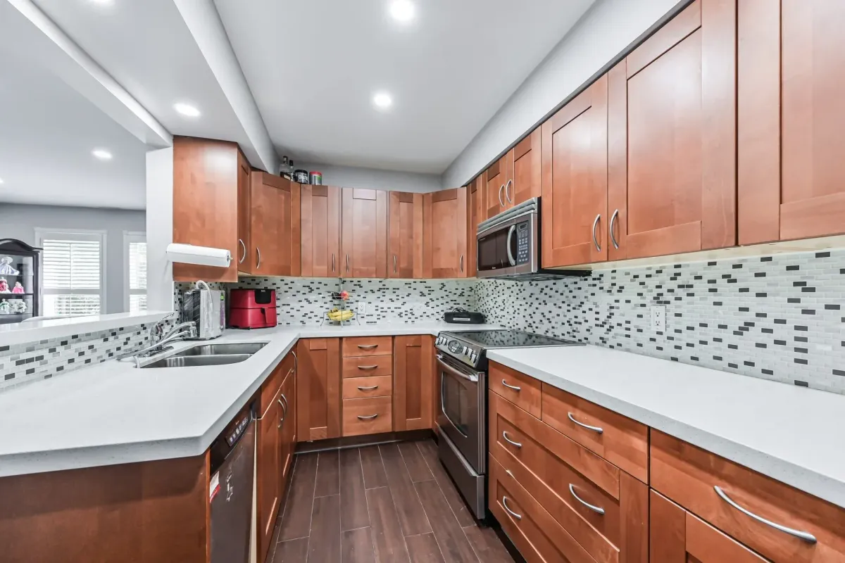 Chef’s kitchen with wood cabinetry and mosaic tile backsplash at 900 Steeles Ave W #112.