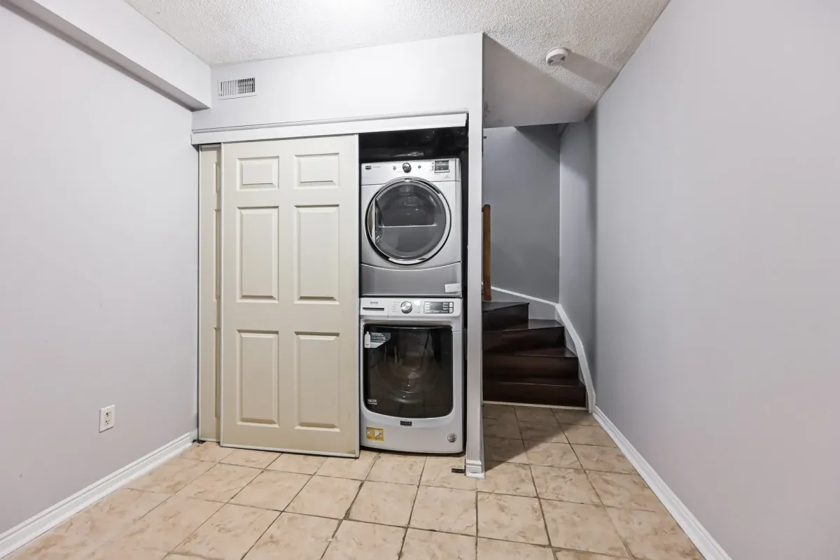 Functional utility area with stacked front-loading washer and dryer at 900 Steeles Ave W #112.