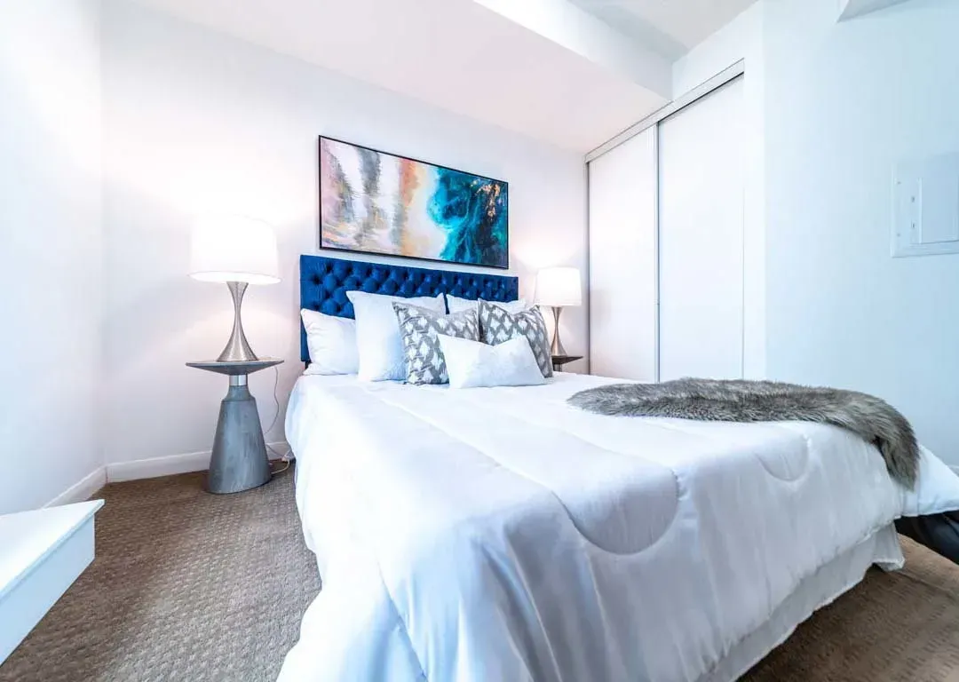 Bright primary bedroom at 235 Sherway Gardens Rd #401 with luxury bedding and terrace access.