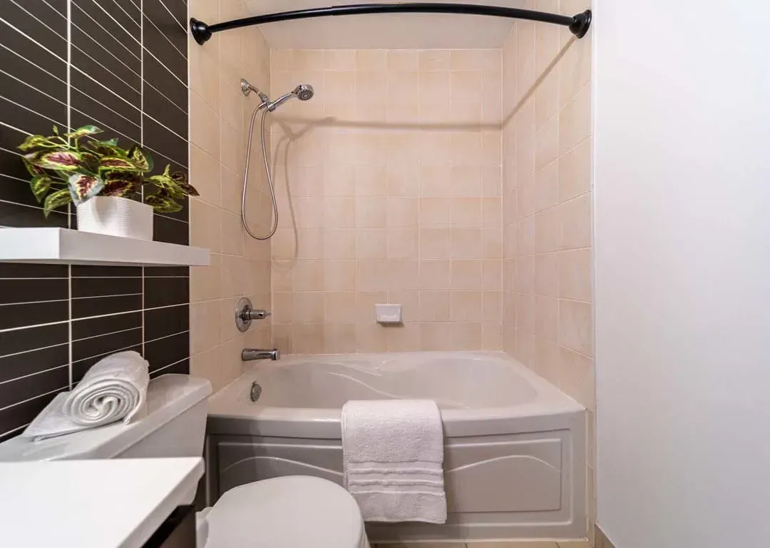 Detailed view of the bathroom at 235 Sherway Gardens Rd #401 featuring a curved shower rod and neutral tiling.