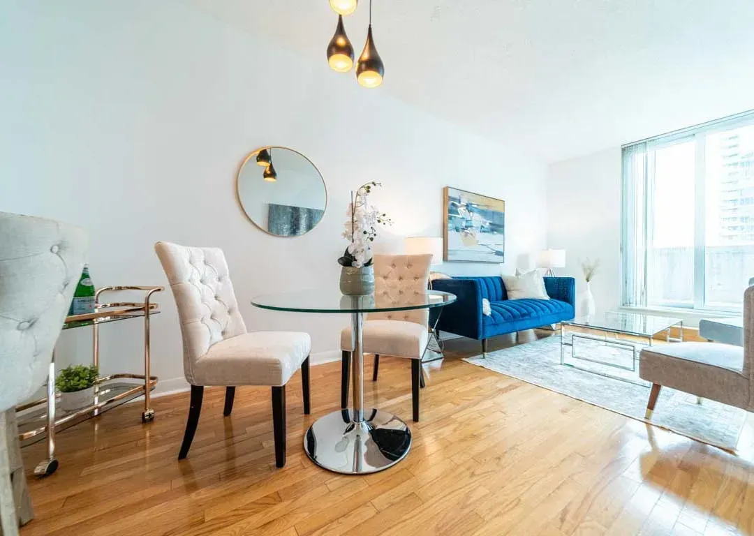 Dining area at 235 Sherway Gardens Rd #401 featuring a glass-top table, chic white chairs, and an elegant gold mirror.