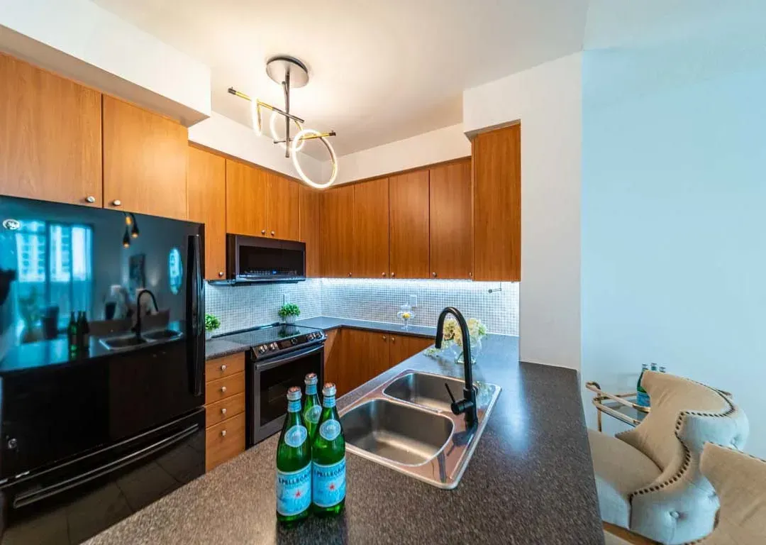 Functional kitchen layout at 235 Sherway Gardens Rd #401 with a breakfast bar and modern black refrigerator.
