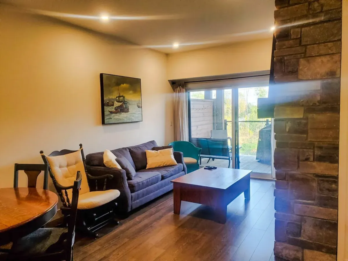 Fully furnished open-concept living room at 11 Beausoleil #105 featuring a grey sofa and warm hardwood floors.