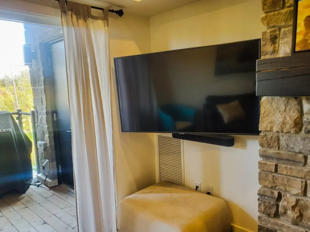 Wall-mounted television and cozy seating area adjacent to the stone fireplace at 11 Beausoleil #105.