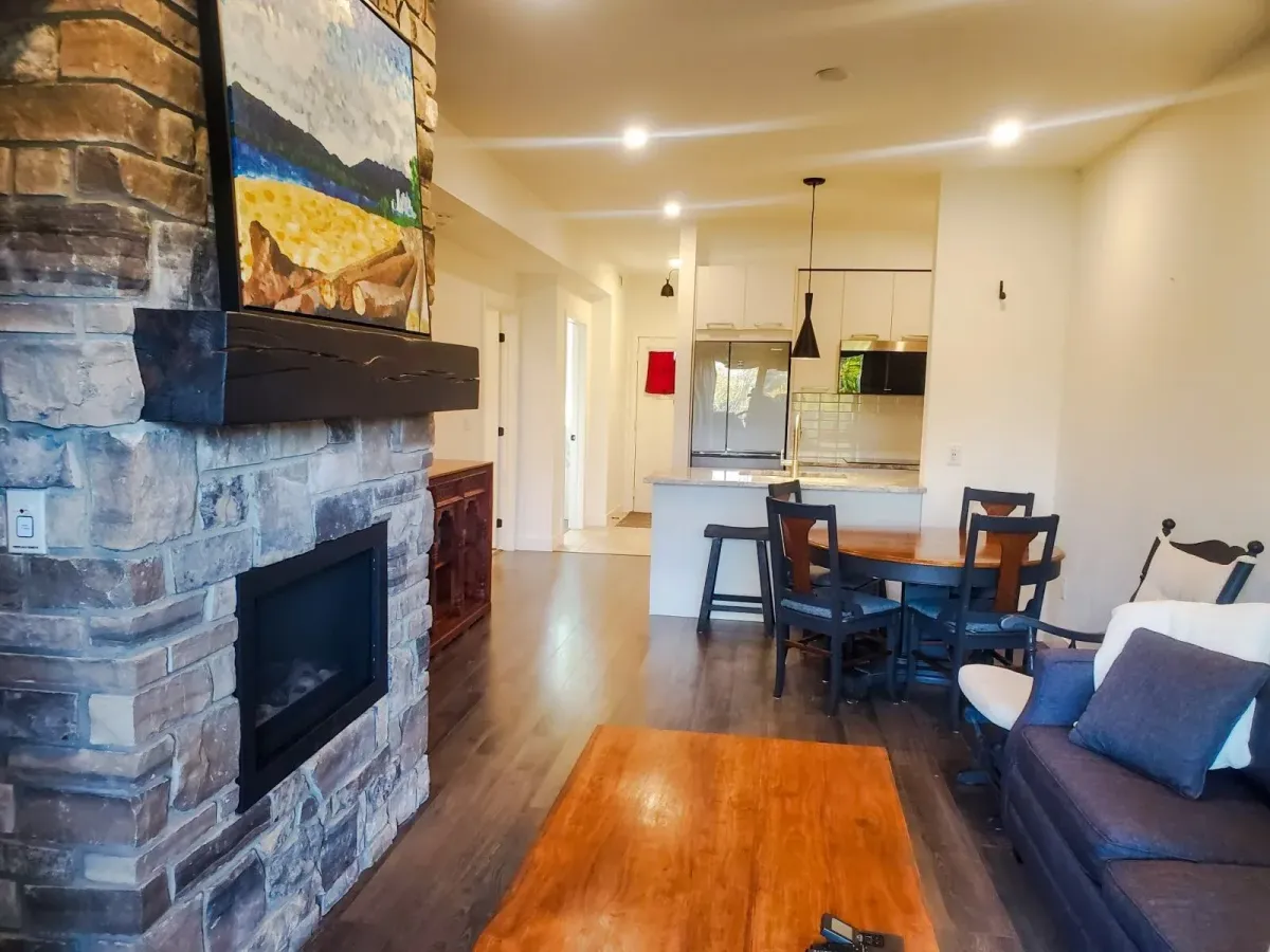 Secondary view of the stone fireplace and timber accents in the main living area of 11 Beausoleil #105.