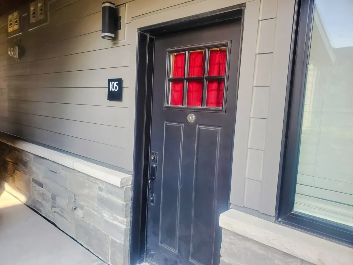 Dark wood entry door with red glass accents for suite #105 at 11 Beausoleil.