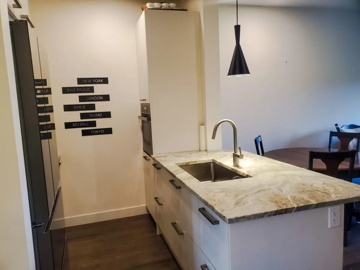 Designer kitchen at 11 Beausoleil #105 showcasing sleek white cabinetry and a breakfast bar island.