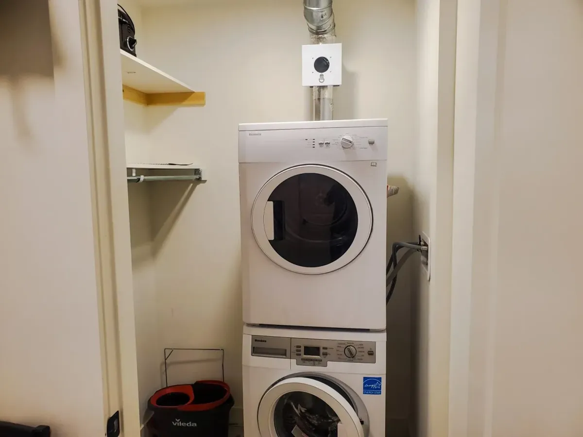 Convenient in-suite laundry closet at 11 Beausoleil #105 with a stacked front-load washer and dryer.