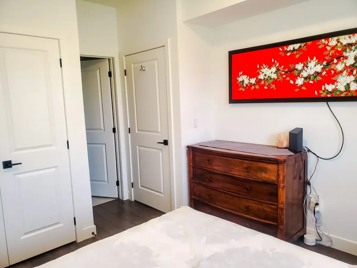 View of the guest bedroom at 11 Beausoleil #105 showing a dark wood dresser and vibrant wall art.