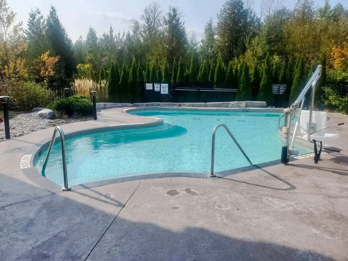 Year-round heated outdoor pool at 11 Beausoleil, surrounded by landscaped gardens and trees.