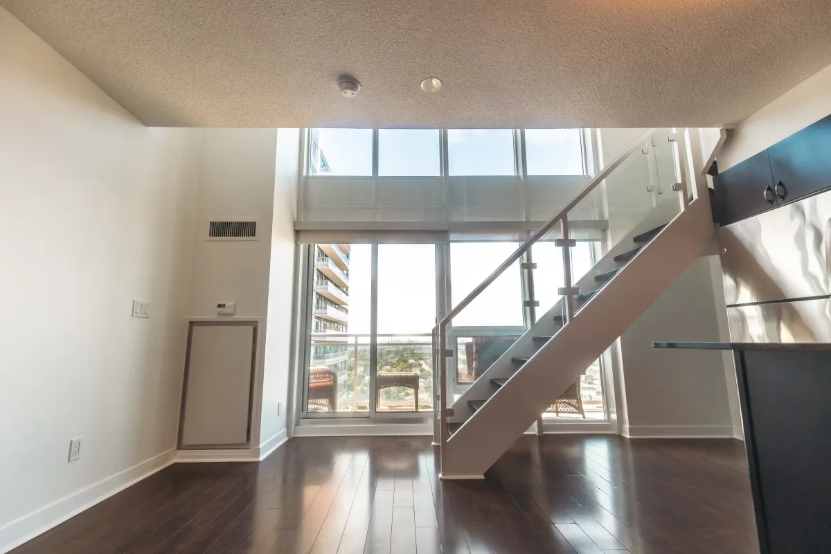 Two-story loft view at 155 Legion Rd N #2311 highlighting the 18-foot ceilings and architectural glass staircase.