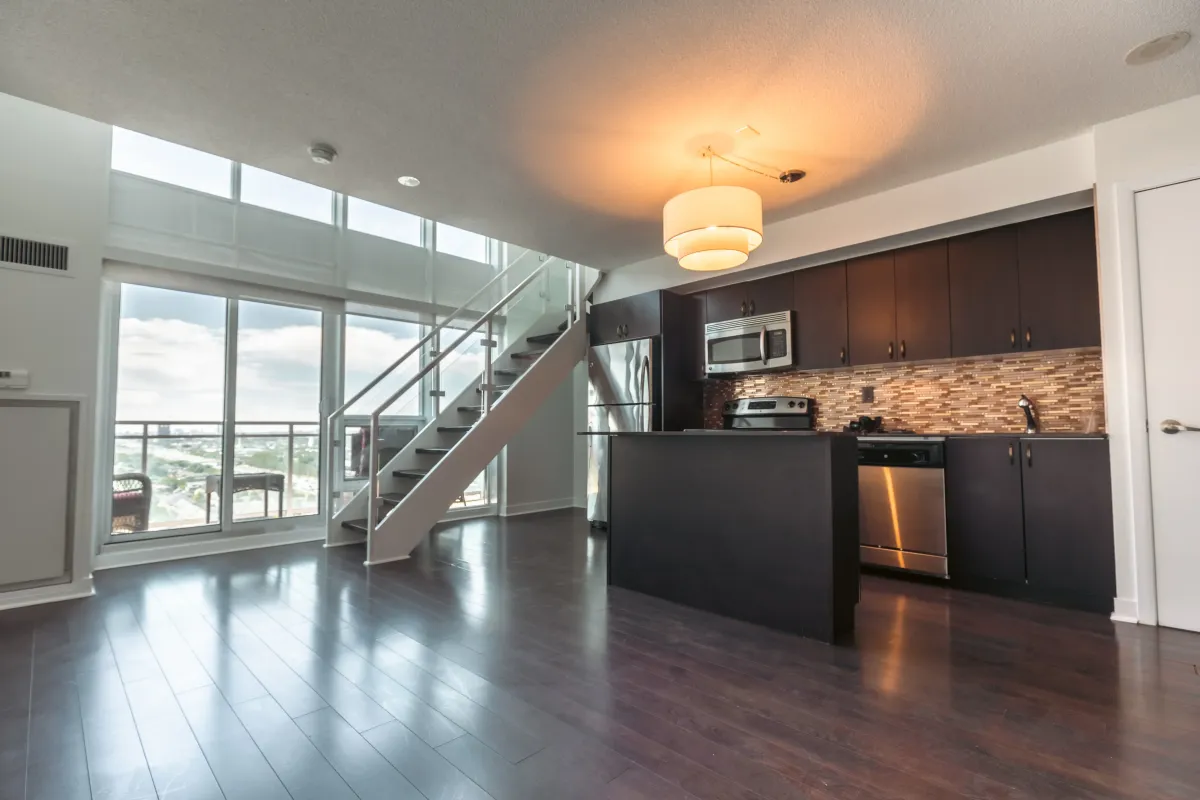 Spacious living room at 155 Legion Rd N #2311 showcasing the dramatic floor-to-ceiling windows and dark hardwood flooring.