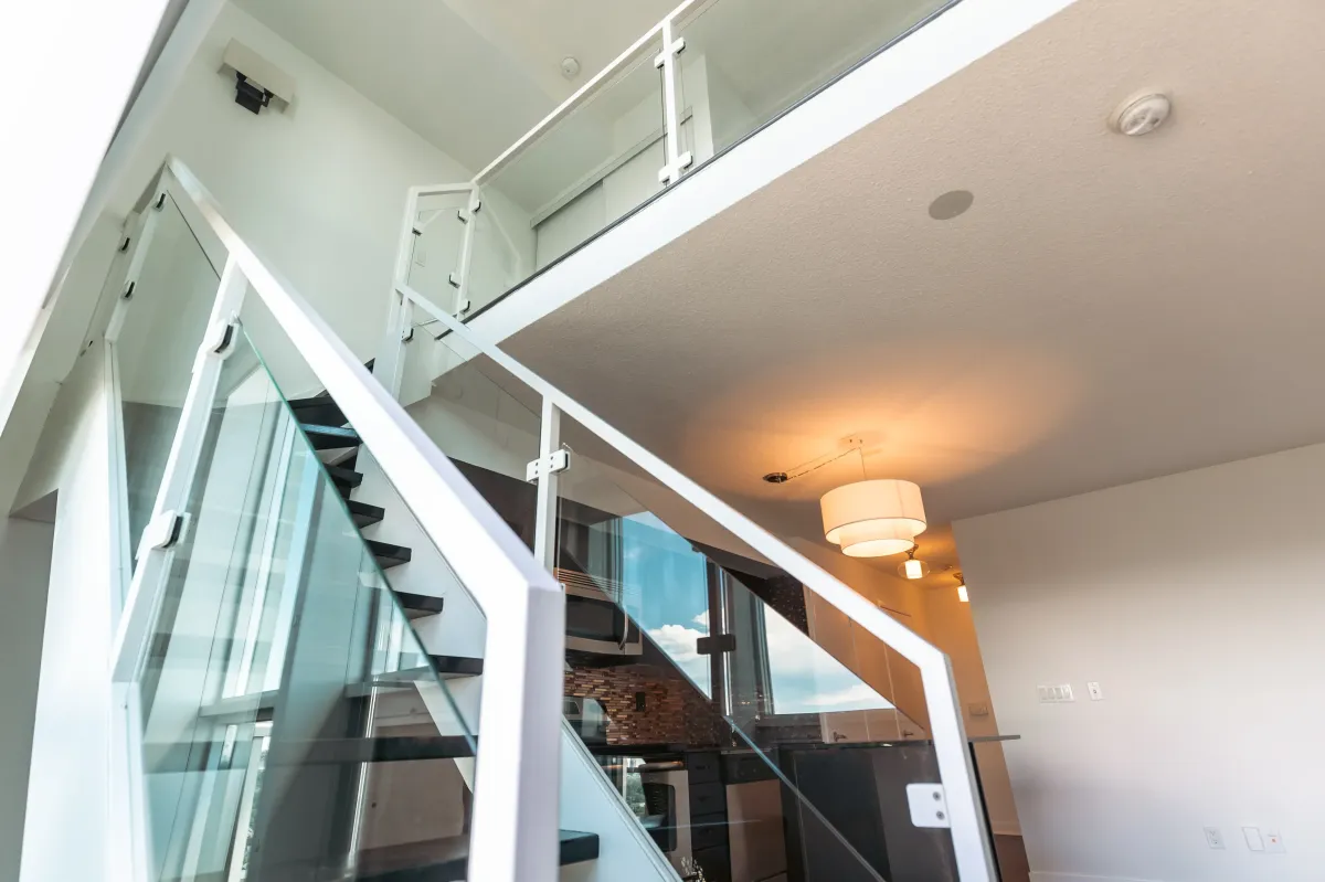 Close-up of the architectural glass and steel staircase leading to the second-floor loft at 155 Legion Rd N #2311.