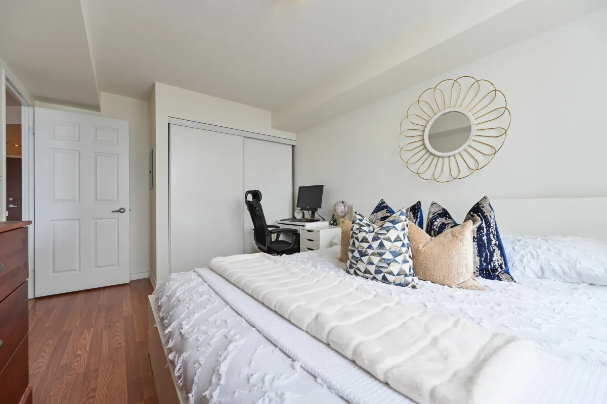 Spacious second bedroom in Suite 1416 at 1369 Bloor St W, highlighting the modern laminate flooring and large closet space.