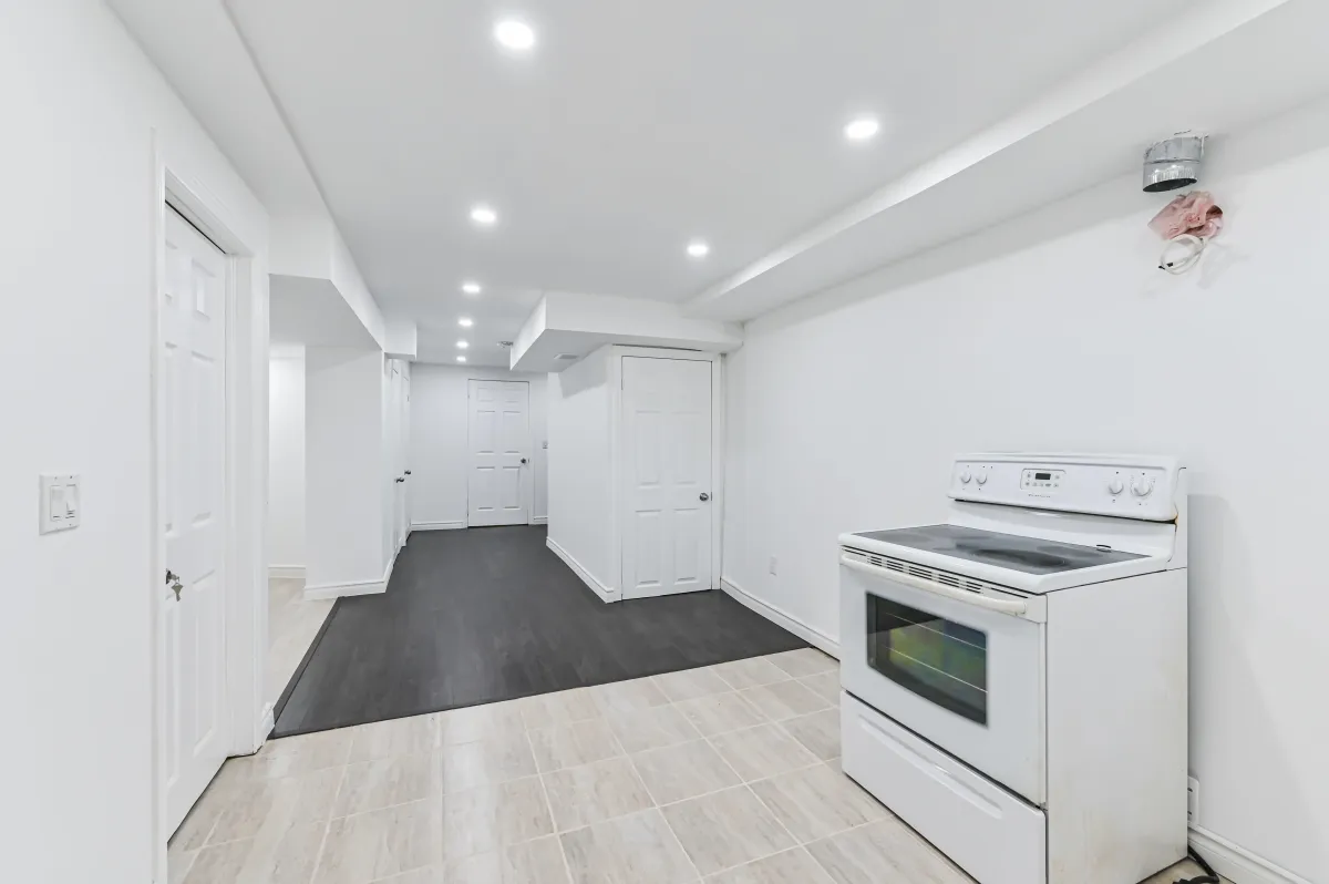 View of the white kitchen appliances and potential second kitchen area in the basement of 133 Howard Crescent.